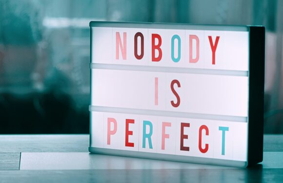 Lightbox display on a tabletop reading “NOBODY IS PERFECT” with colorful letters against a soft blue background.