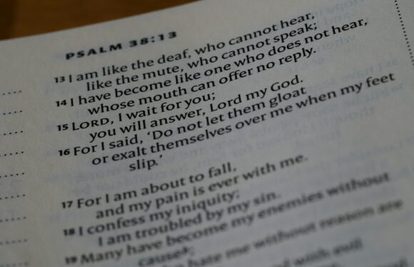 A close-up of an open Bible displaying Psalm 38:13-18, with text about deafness, waiting for the Lord, and seeking help amidst pain and trouble.