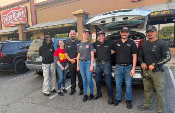 Seven employees pose in front of a white delivery truck outside Pizza Ranch, with storefront signage reading Carry Out.