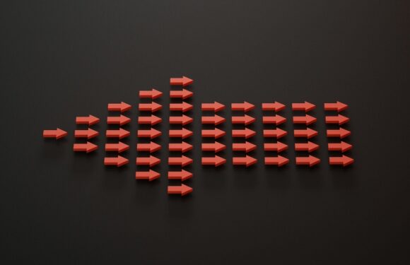 Red 3D arrows arranged like a wave, forming a long burst shape over a dark gray background, pointing rightward.