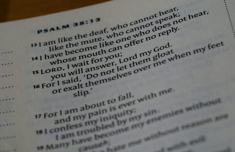 A close-up of an open Bible displaying Psalm 38:13-18, with text about deafness, waiting for the Lord, and seeking help amidst pain and trouble.
