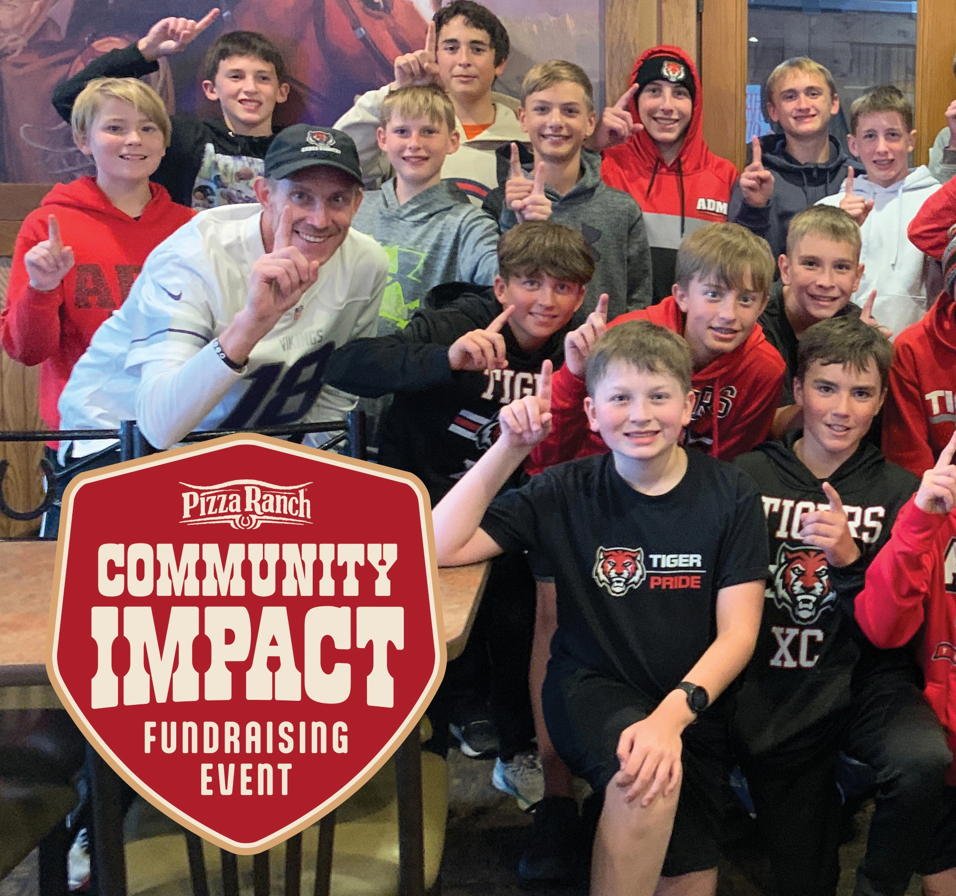 Group of kids and an adult giving a thumbs-up inside a restaurant, with a Pizza Ranch Community Impact Fundraising Event sign in front.